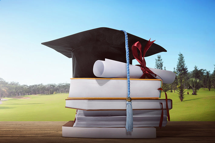 Image of academic concepts. A graduation hat with hardback thesis, dissertations and repots stacked up, with a graduation scroll